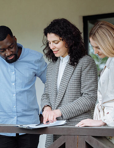 Three professionals discussing documents together in an office setting.