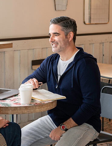Man in casual wear working with notebook and coffee at a cafe.