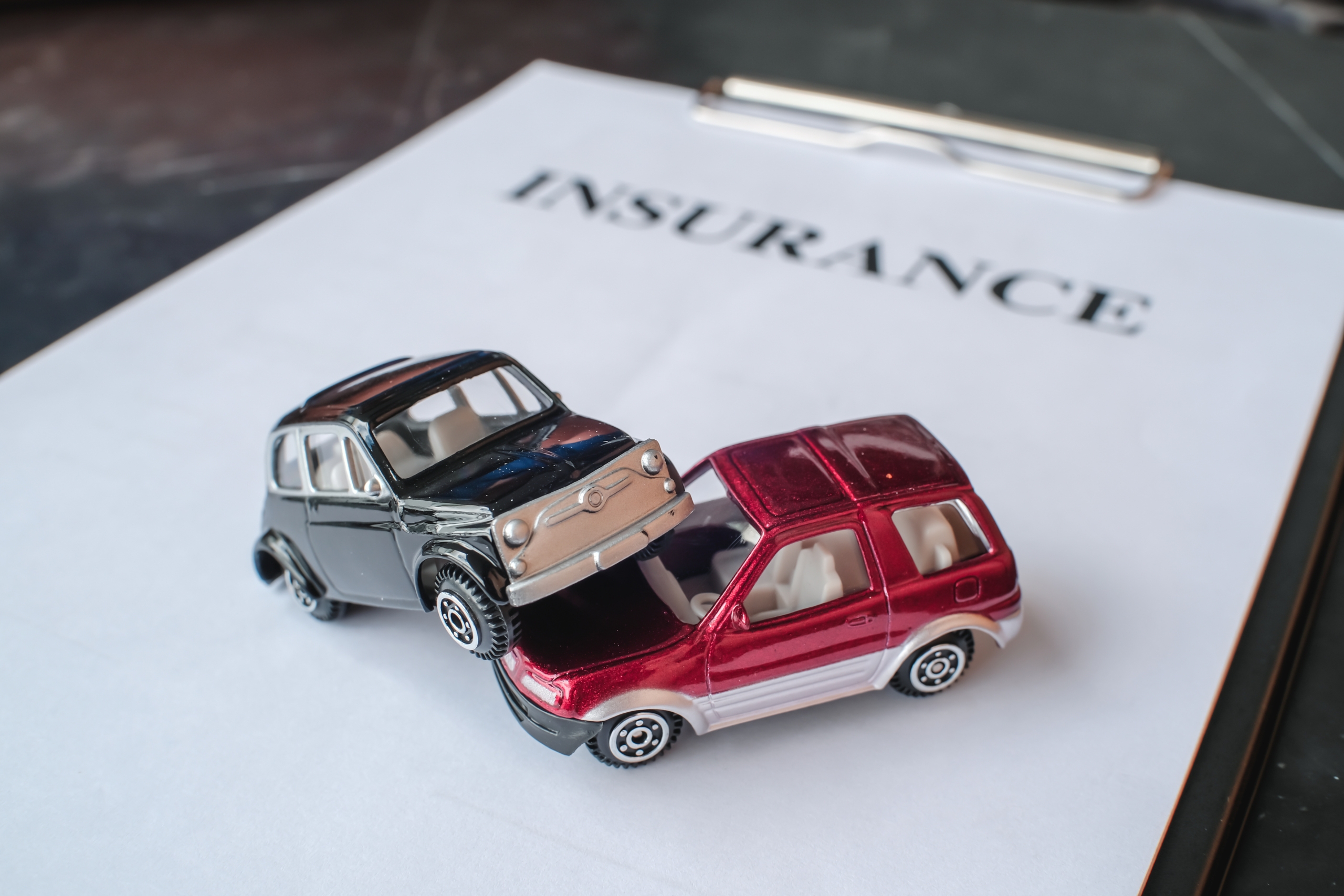 Two toy cars in a crash on an insurance document.