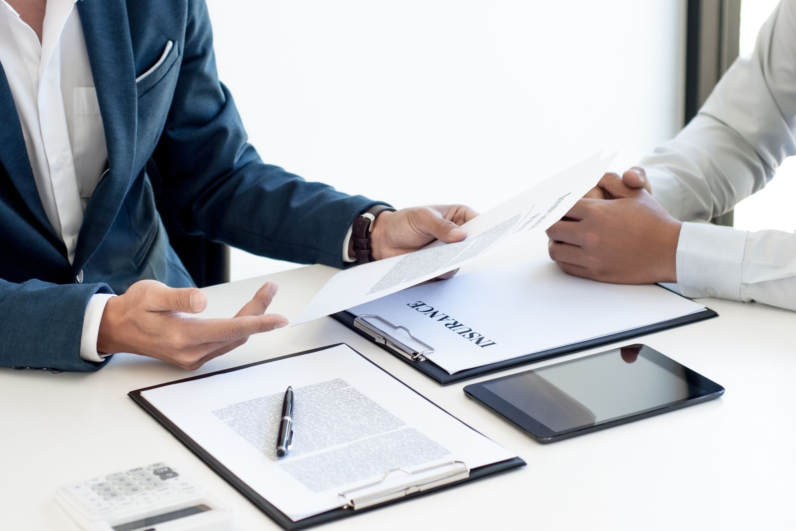 Two business professionals reviewing insurance documents at a desk.