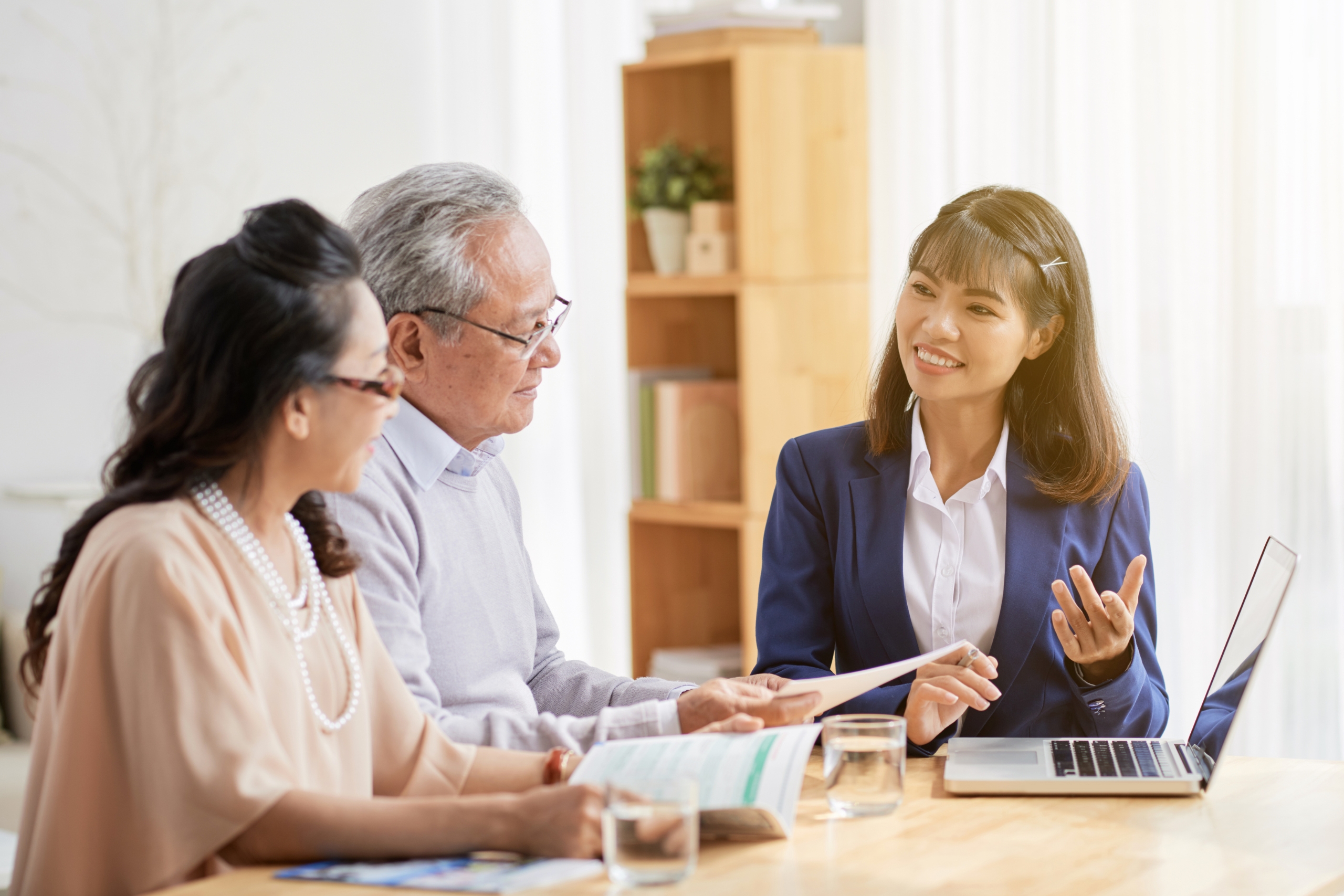 A consultant discussing financial plans with an elderly couple in a bright office.