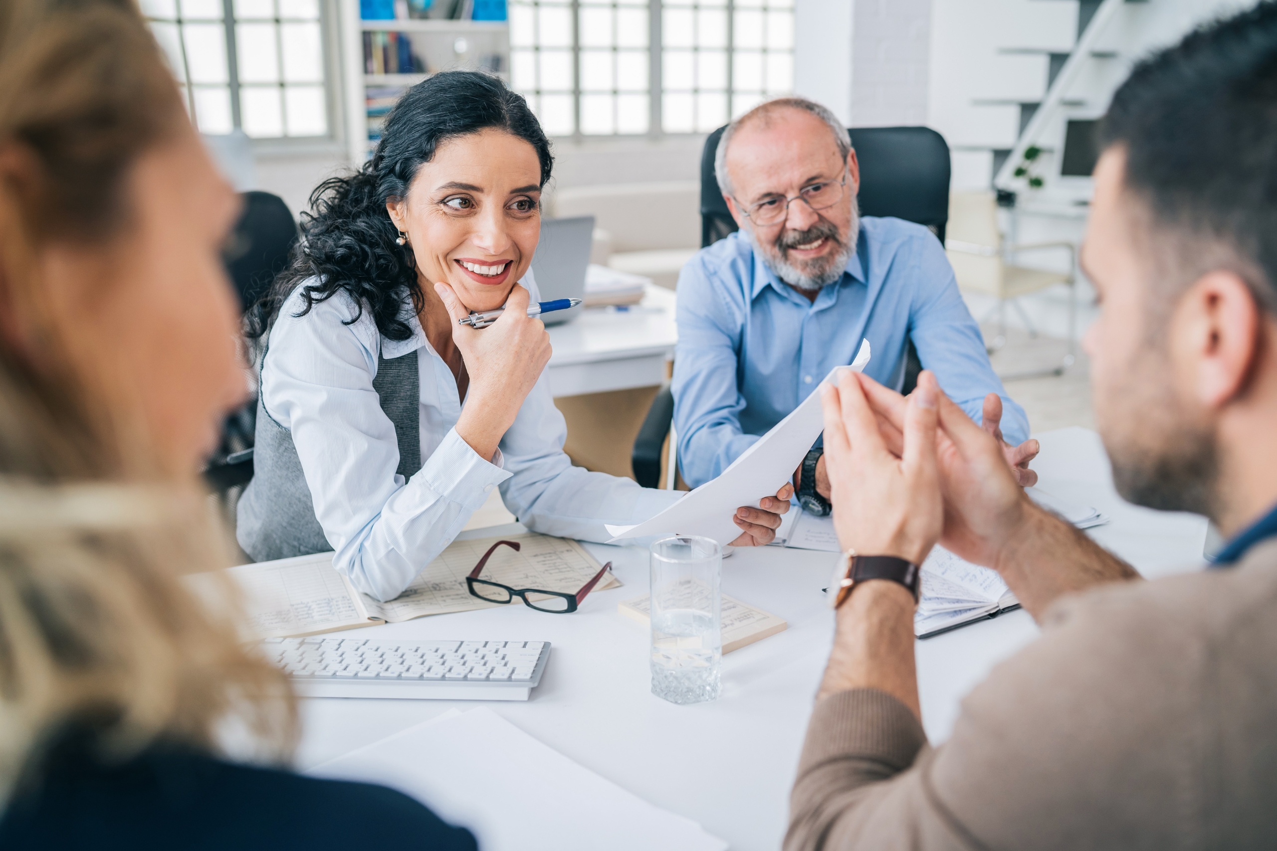 Four colleagues engaged in a lively office discussion around a desk.