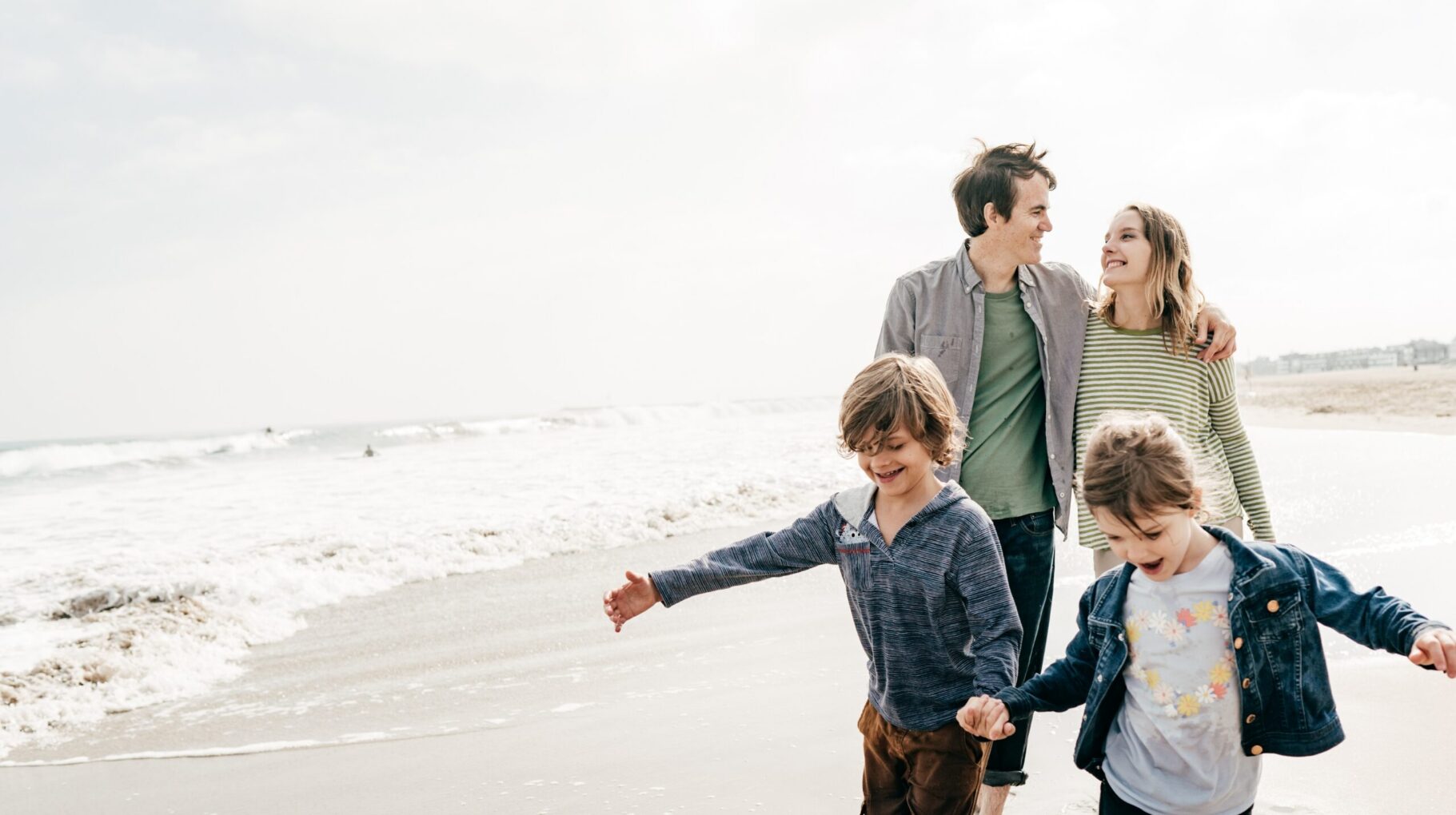 A joyful family walking along a beach on a bright day.