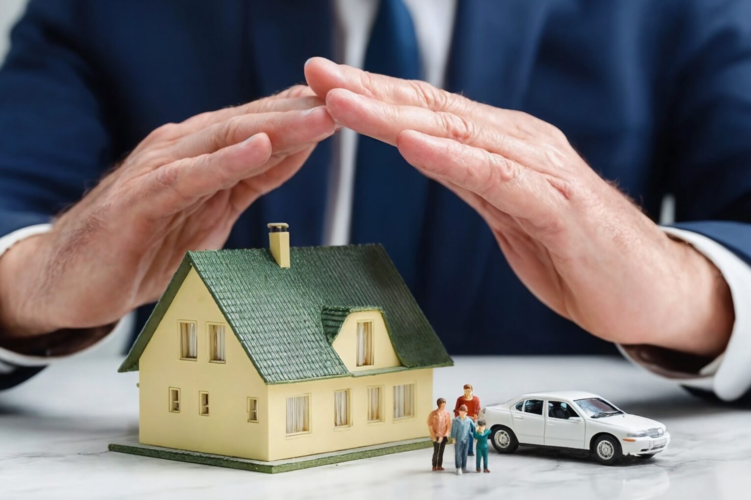 Hands protect a miniature house, family, and car, symbolizing insurance and safety.