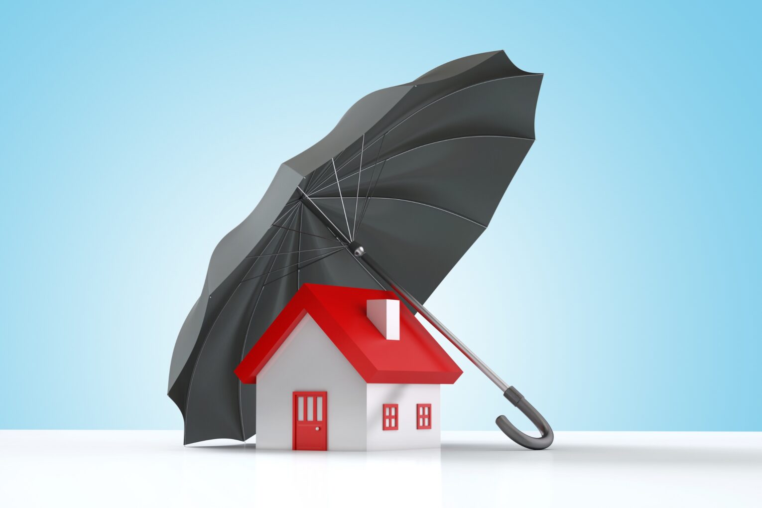 A small house with a red roof protected by a large black umbrella.